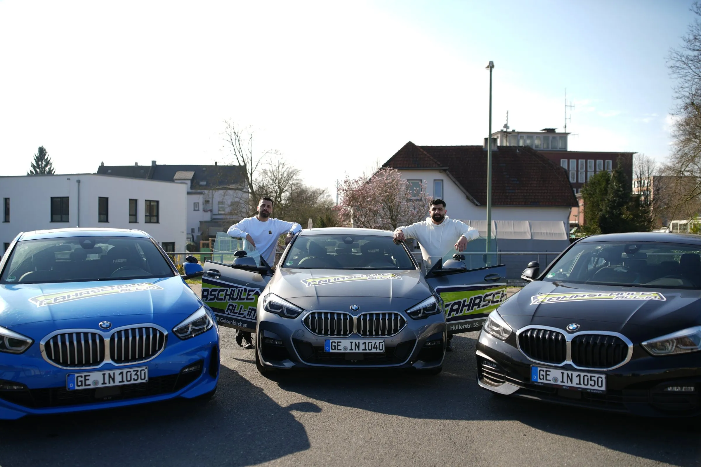 Team der Fahrschule All-in zwischen den Fahrschulautos